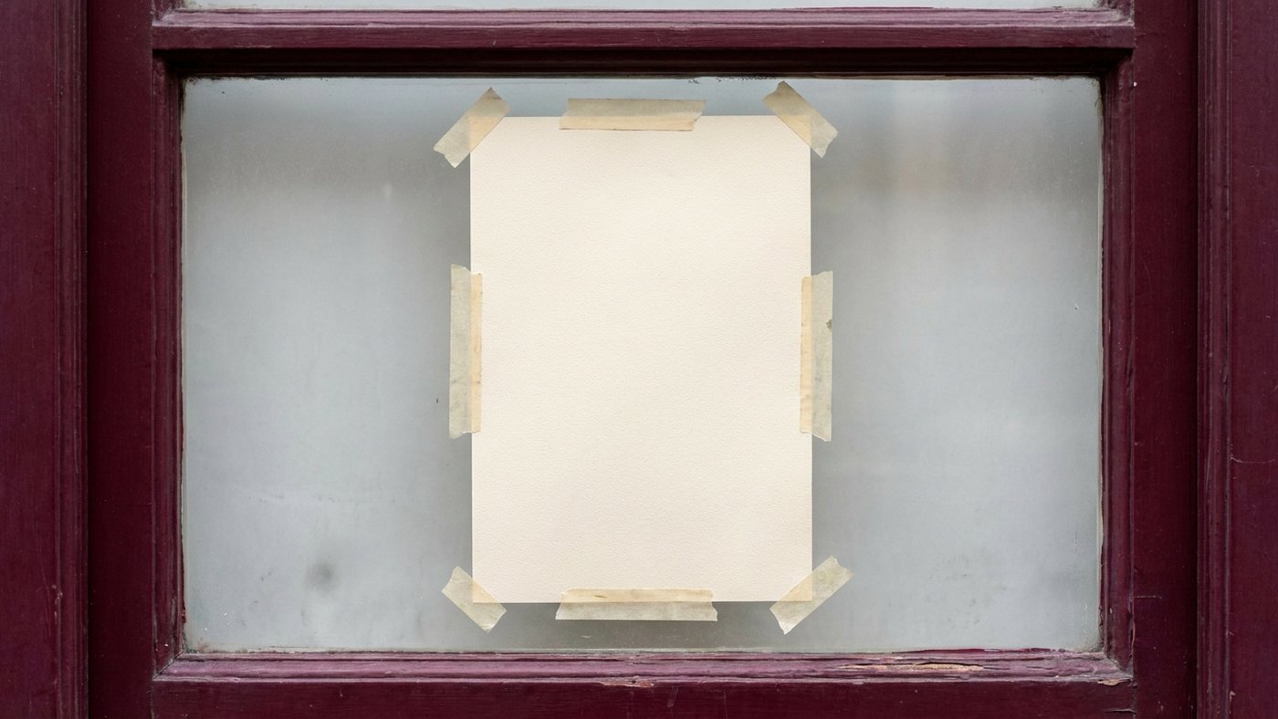 Affiche de papier vierge scotchée derrière la vitre dépolie d'une devanture en bois bordeaux