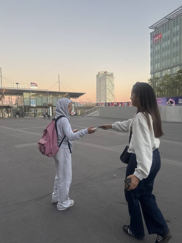 Une animatrice Dove Gospel remet un flyer près de la gare de Saint-Denis