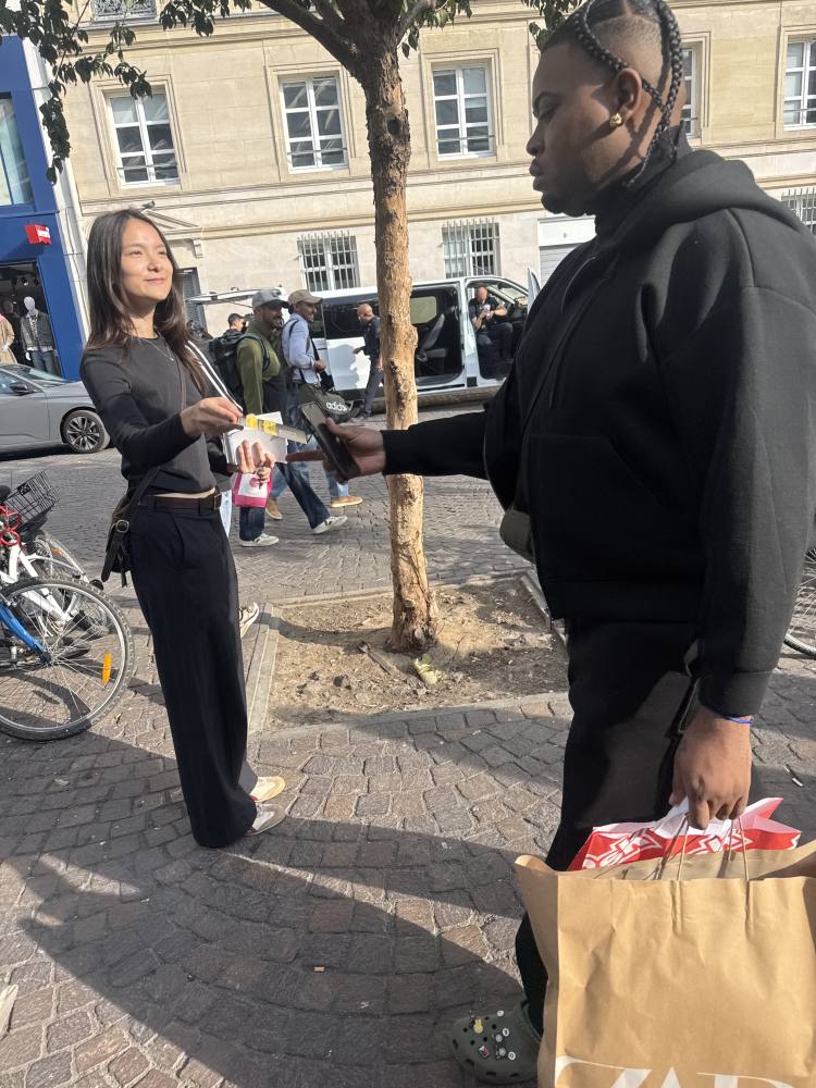 Une animatrice remet un flyer Metro-Taxi à un passant près de Châtelet à Paris