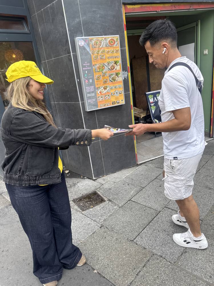 Un animateur Western Union remet un flyer à un passant à Belleville, Paris