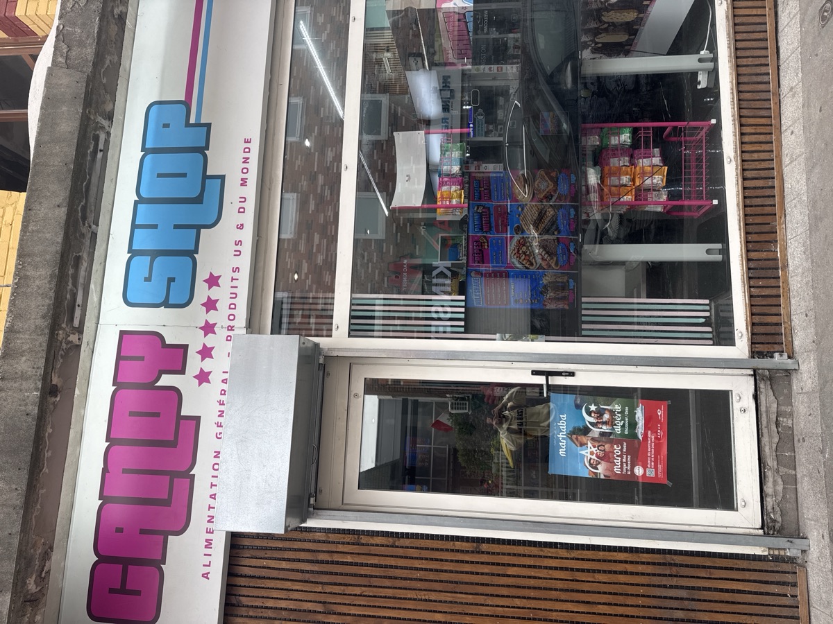 Affiche posée en vitrine d'une épicerie de la Grande Rue à Roubaix